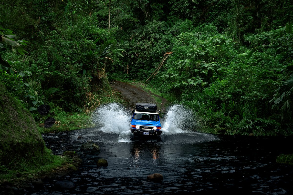 Blue Toyota FJ Cruiser driving through a jungle river