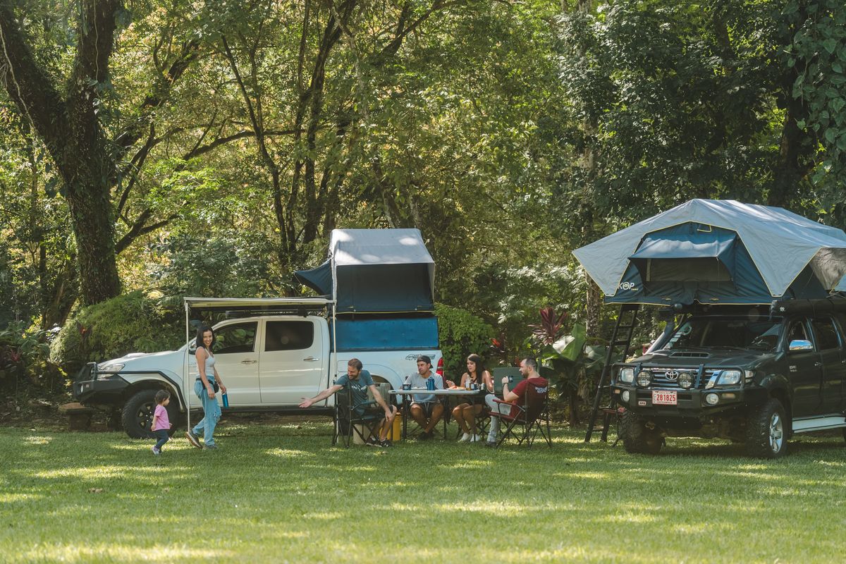 Friends eating at a camp table between two Toyota Hilux campers