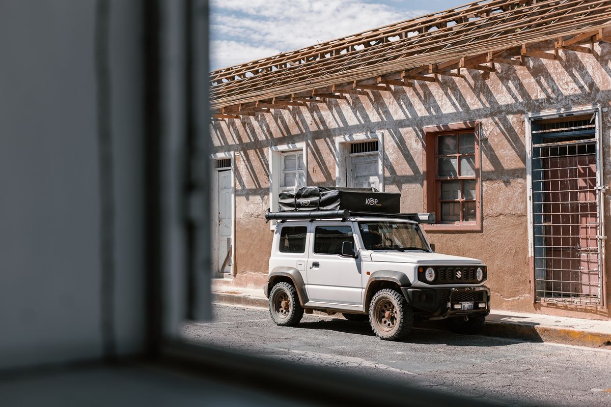 Suzuki Jimny with a rooftop tent parked on a colonial street