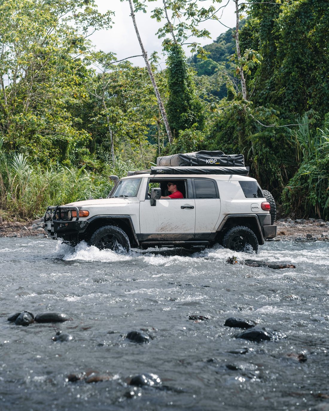 Toyota FJ Cruiser crossing a river in the rainforest