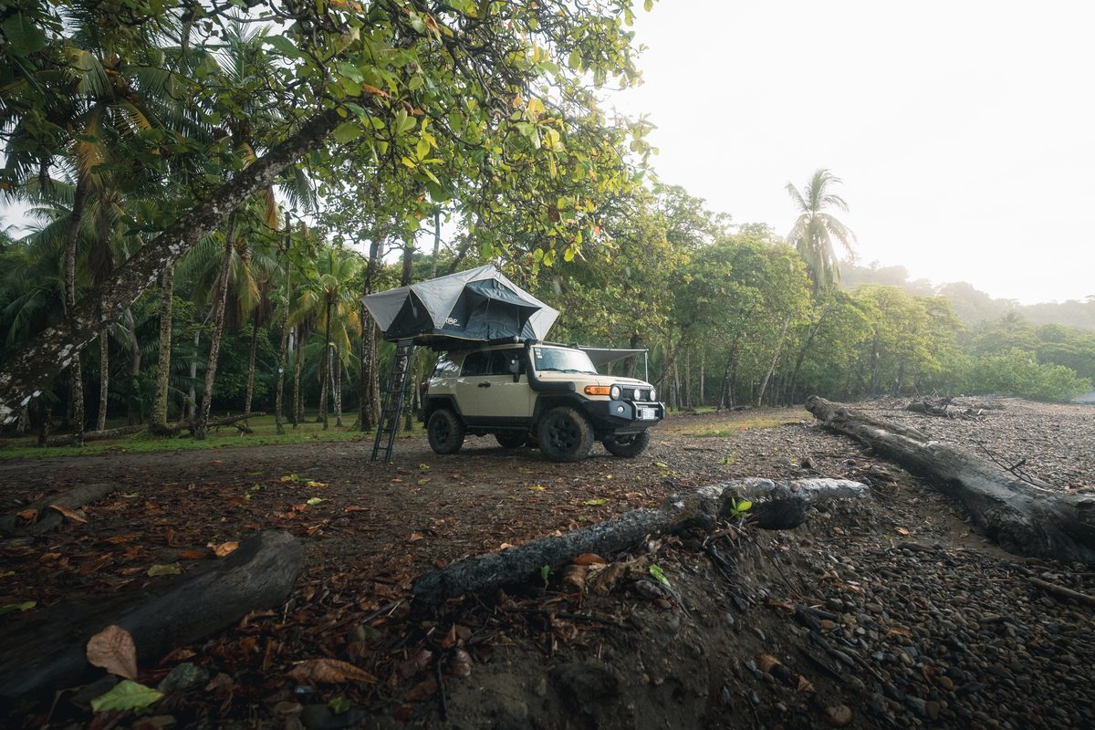 Toyota FJ Cruiser with its rooftop tent open under large trees