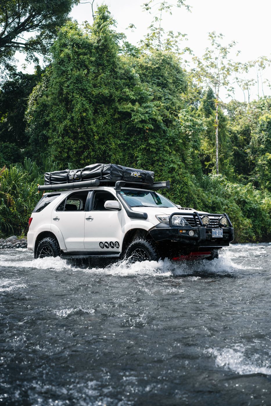 Toyota Fortuner crossing a river below dense jungle