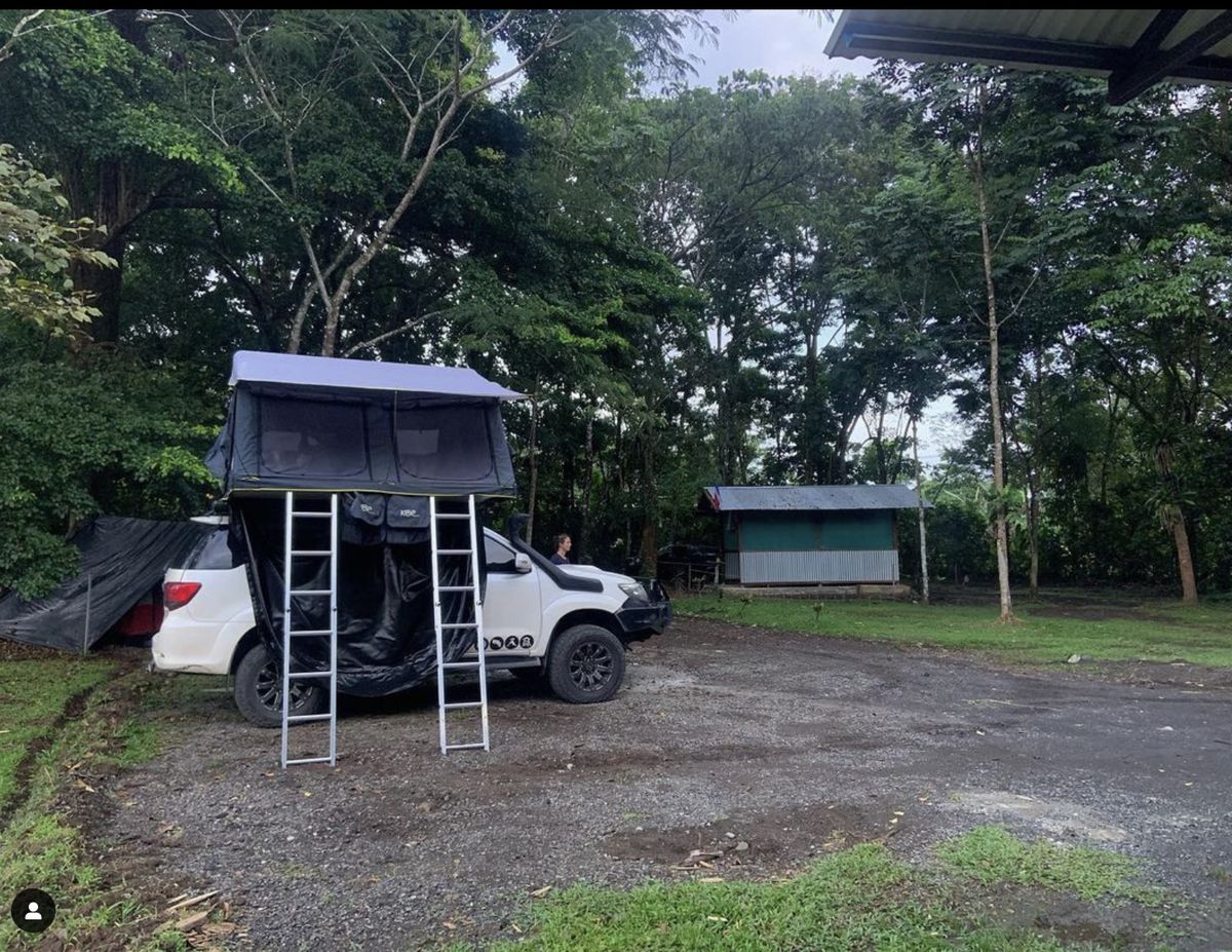 Toyota Fortuner with the wide double rooftop tent open at a campsite