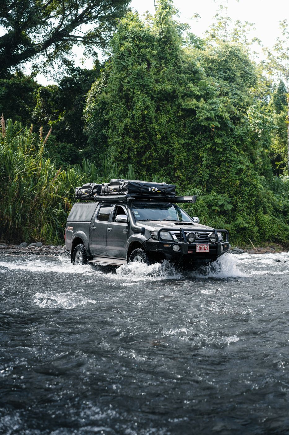 Toyota Hilux crossing a river in the rainforest