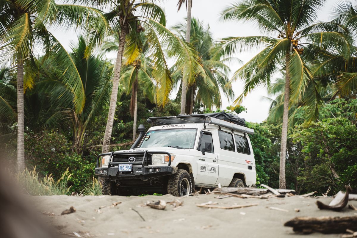 Toyota Land Cruiser Troopie parked among palms on a beach