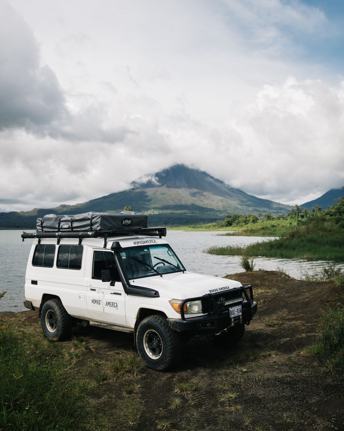 Toyota Land Cruiser Troopie parked by a lake below a volcano