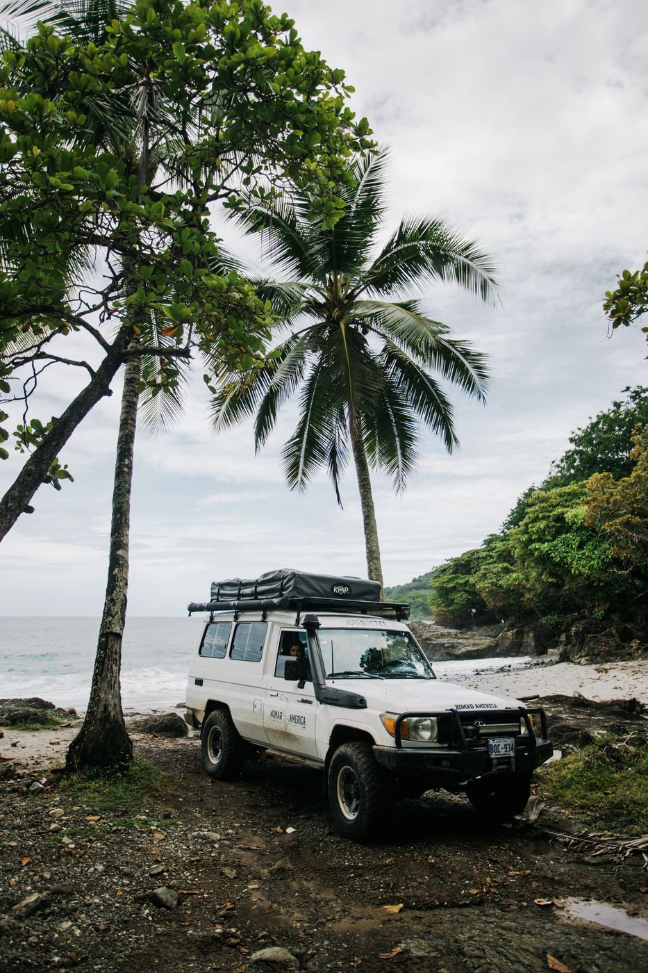 Toyota Land Cruiser Troopie parked on a palm-lined beach