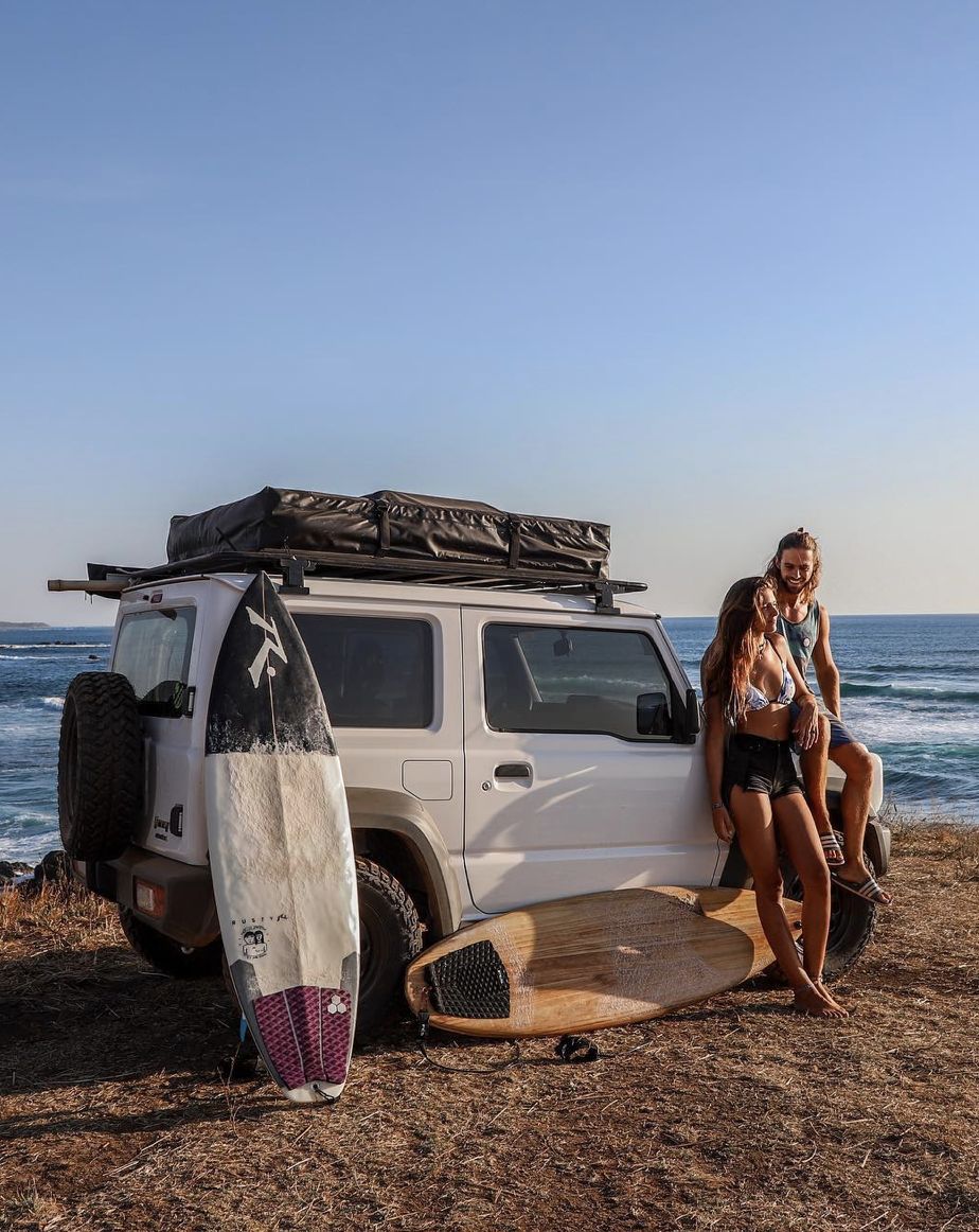 White Suzuki Jimny with surfboards by the sea